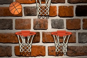 Basketbalová lopta a tri basketbalové koše na tehlovom múre