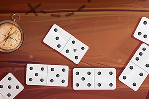Kompás a rozložené domino na drevenom povrchu