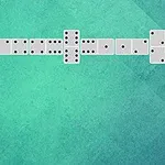 Domino kocky usporiadané na zelenom pozadí v tvare pravého uhla