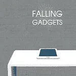 Tablet leží na bielom stole pred sivou tehlovou stenou s textom Falling Gadgets nad ním