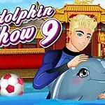 Blond muž v modrých plavkách objímajúci delfína, s farebnou loptou a orientálnou budovou v pozadí