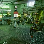 Kaviareň s robotmi, ktoré sedia pri stolíkoch a barovým pultom s nápisom Le Robotbar