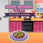 Animovaná postava kuchárky stojí v kuchyni vedľa stola s pokrmom a nápisom Saras Cooking Class
