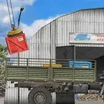 Nákladné auto stojace pred skladiskom s nápisom Cargo Delivery a žeriav zdvíhajúci červený kontajner